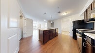 This single-floor residence offers a thoughtfully designed layout across three bedrooms and three full bathrooms, making it a practical and comfortable living space. The open-concept kitchen and living area serves as the heart of the home, highlighted by a central island with dark espresso cabinetry, a built-in sink, and pendant lighting overhead. The kitchen is further equipped with black appliances, including a refrigerator and range, along with ample counter and cabinet storage. Warm hardwood-style flooring flows throughout the main living areas, creating a cohesive and inviting ambiance.

The living room extends naturally from the kitchen, featuring a ceiling fan and windows fitted with blinds that allow for natural light. The bedrooms offer a mix of flooring options — some with plush carpeting and others with hardwood-style floors — and each is served by windows that bring in additional natural light. The primary bedroom provides a comfortable, well-sized retreat.

The three bathrooms are consistently finished with light tile flooring, dark wood vanities, white countertops, and tub-shower combinations. A dedicated in-unit laundry room with a full-size washer and dryer adds everyday convenience. Additional features include a hallway, closet, and a clean, neutral color palette throughout.