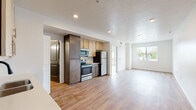 Located at 8255 West Limelight Street in Boise, Idaho, this single-floor residence offers a thoughtfully designed open-concept layout with a clean, modern aesthetic throughout. Warm light wood flooring runs continuously across the living areas, creating a cohesive and inviting atmosphere.

The kitchen is well-appointed with a two-tone cabinet design, combining light maple upper cabinets with rich dark lower cabinets. A marble-style tile backsplash adds a refined touch, while the countertops provide ample prep space. The kitchen is fully equipped with stainless steel appliances, including a refrigerator, electric range, over-the-range microwave, and dishwasher. Recessed lighting illuminates the space effectively.

The open living area is bright and spacious, benefiting from natural light and offering direct access to a private balcony through sliding glass doors. The balcony provides pleasant outdoor views of the surrounding neighborhood. A ceiling fan adds comfort to the living space.

The bathroom features a vanity with dark wood cabinetry, a combined tub and shower, and matte black fixtures and hardware that lend a contemporary edge. Additional utility space is incorporated discreetly within the unit. Charcoal-toned interior doors with panel detailing provide a stylish contrast against the crisp white walls throughout.