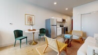 This well-appointed studio offers a smart, open-plan layout that maximizes every square foot of its single-floor footprint. Polished concrete floors run throughout, lending an industrial-modern character that ties the entire space together cohesively.

The kitchen is fully equipped with stainless steel appliances—including a full-size refrigerator, range, and microwave—complemented by crisp white cabinetry and a clean countertop workspace. A cozy dining nook sits just adjacent, providing a defined area for meals without interrupting the open flow.

The living area is generously proportioned, featuring recessed lighting and soft, neutral walls painted in a calming light blue-gray tone. A wall-mounted mini-split system ensures year-round climate control. The sleeping area flows naturally from the living space, offering ample room for a full bedroom setup and benefiting from a window that draws in natural light.

The bathroom is divided into distinct compartments: a dedicated toilet room with clean white walls, a separate walk-in shower with floor-to-ceiling white tile surround, and a vanity area—providing a level of privacy and function uncommon in a studio layout. The result is a compact yet highly functional space that balances modern industrial aesthetics with everyday comfort.