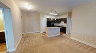 This single-floor residence is designed with a practical, open-concept layout that connects the kitchen and living areas seamlessly. The kitchen is a standout feature, equipped with dark espresso cabinetry offering ample storage, granite countertops, a central island with additional seating, and a full suite of black appliances including a gas range, refrigerator, dishwasher, and microwave. A skylight above the kitchen brightens the space with natural light, while pendant lighting adds a polished finishing touch. The living area extends from the kitchen and is finished with neutral-toned carpet, creating a warm, cohesive feel throughout.

The bedrooms are comfortably sized, each featuring plush carpeting, neutral walls, and windows with blinds that allow for natural light and privacy. One bedroom includes access to an exterior door, offering added convenience.

Both bathrooms are well-appointed with granite-topped dark vanities, tub-shower combinations with tiled surrounds, and wood-look flooring. One bathroom features built-in wall shelving for additional storage. The entryway is finished with wood-look flooring and provides access to a utility or storage area. Throughout the unit, white trim and neutral tones create a clean, consistent aesthetic.