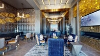 This expansive, single-floor luxury lounge space is a masterclass in contemporary upscale design. The interior is defined by soaring ceilings with coffered, gold-trimmed details and layered ambient lighting, including statement chandeliers and pendant fixtures that cast a warm, inviting glow throughout. Rich materials are found at every turn — from intricate mosaic tile accent walls in bronze and gold hues to textured stone-look flooring laid in herringbone and large-format patterns.

The space is organized into a series of distinct yet interconnected areas. A central corridor-style lounge features deep navy velvet sofas and gold-accented armchairs arranged around low tables, creating an elegant gathering hub. Adjacent seating nooks offer more intimate settings, with tufted leather banquettes, curated wall art, and dramatic patterned wallcoverings. A bar-height counter with terracotta seating and pendant globe lighting provides a stylish perch beside floor-to-ceiling windows that flood the space with natural light and offer open views of the surrounding exterior.

A retail display area showcases apparel on a mannequin alongside a glass vitrine, accented by a gold mosaic feature wall. Toward the perimeter, a game area with a billiards table and a plush lounge with LED-lit furniture and panoramic windows round out the space, creating a dynamic, resort-caliber environment.