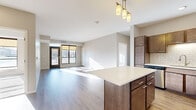 This single-floor residence features a thoughtfully designed open-concept layout that connects the kitchen and living area seamlessly. The kitchen is well-appointed with rich, dark-toned cabinetry, stainless steel appliances including a refrigerator, range, and microwave, a white subway tile backsplash, and a central island with a clean white countertop. Pendant lighting above the island adds a modern touch. Wood-style flooring runs throughout the main living areas, complementing the neutral wall tones and white trim.

The living area is bright and airy, benefiting from large windows and a glass-panel door that opens to a private balcony, allowing generous natural light and outdoor views. The two bedrooms are carpeted and well-sized, each featuring large windows that continue the theme of natural light. One bedroom provides direct access to a bathroom, offering added convenience.

The two bathrooms are finished with large-format tile flooring, dark wood vanities, white countertops, and tub-shower combinations with chrome fixtures. A washer and dryer are also included within the unit. Overall, the space presents a clean, contemporary aesthetic with functional, modern finishes throughout.
