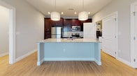 Located at 151 Oakland Rd in South Windsor, Connecticut, this single-floor residence offers a thoughtfully designed open-concept layout that seamlessly connects the living, dining, and kitchen areas. Light wood-style flooring flows throughout the main living spaces, creating a warm and cohesive aesthetic, while neutral-toned walls provide a clean, move-in-ready backdrop.

The kitchen is a standout feature, showcasing rich dark cabinetry, granite countertops with subtle veining, and a large center island with pendant lighting above. Stainless steel appliances — including a refrigerator, range, microwave, and dishwasher — complete the functional and stylish cooking space. A dedicated laundry area with a full-size washer is conveniently accessible directly from the kitchen.

The bedroom areas are finished with plush carpeting and include generous walk-in closet space outfitted with wire shelving systems. One bedroom benefits from a sliding glass door and an additional window, allowing for abundant natural light and outdoor access. The bathroom features large-format tile flooring, a dark-cabinetry vanity with a white countertop, and a shower-tub combination. The entry foyer, also finished in light wood-style flooring, welcomes residents with bright windows and direct outdoor views.