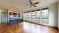 Located at 5151 Hidalgo Street in Houston's Galleria area, this well-appointed two-bedroom, two-bathroom residence offers a thoughtfully designed single-floor layout. The open-concept living and kitchen area is a standout, featuring rich hardwood floors, a large center island with a sleek quartz countertop, pendant lighting, and dark espresso cabinetry paired with stainless steel appliances. A built-in shelving unit and wine storage add functional character to the space. A wall of floor-to-ceiling windows floods the living area with natural light and provides views of surrounding greenery.

The primary bedroom is generously sized, featuring warm hardwood flooring, a ceiling fan, and a bank of large windows. It is complemented by a walk-in closet with built-in shelving and hanging rods. The second bedroom offers plush carpeting, a ceiling fan, and its own windows with city views. Both bathrooms are finished with light tile flooring, grey vanity cabinetry, and tiled tub-shower combinations with built-in niches.

A dedicated laundry room houses a full-size washer and dryer with overhead cabinetry for additional storage. The hallway connects all areas efficiently, completing this practical and modern urban residence.