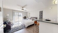 Located at 4500 Woodman Ave in the heart of Sherman Oaks, Los Angeles, this well-appointed one-bedroom, two-bathroom unit offers a thoughtfully designed single-floor layout that maximizes every square foot. The exterior of the building showcases a classic white stucco facade with decorative lattice details and navy awnings, lending a distinct character to the property.

The generously sized primary bedroom serves as the centerpiece of the unit, featuring warm wood-look flooring, a ceiling fan with light fixture, and sliding glass doors that open onto a private balcony, allowing natural light to fill the space. Built-in cabinetry and two closets — one of which is a walk-in — provide ample storage. A cozy seating area within the bedroom adds versatility to the room.

The kitchen is efficiently designed with white shaker-style cabinetry, dark countertops, stainless steel appliances including a refrigerator and over-the-range microwave, and a breakfast bar that doubles as a dining area. Both bathrooms are finished with white vanities, gray countertops, large mirrors, and wood-look flooring, with one bathroom featuring a shower-tub combination. The overall aesthetic is clean, modern, and cohesive throughout.