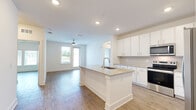 This single-story Jacksonville, FL home offers a thoughtfully designed open-concept layout with 2 bedrooms, 3 bathrooms, a dedicated laundry room, and two closets. The kitchen serves as a central focal point, showcasing granite countertops, a large island with an undermount sink, white shaker cabinetry reaching to the ceiling, a tile backsplash, and a full suite of stainless steel appliances including a refrigerator with ice maker, electric range, and microwave. The kitchen flows seamlessly into the living area, which features wood-look flooring, recessed lighting, and a ceiling fan. Both bedrooms are bright and comfortable, each equipped with ceiling fans, wood-look flooring, and large windows with blinds that invite generous natural light. The primary bedroom includes access to a spacious walk-in closet with wire shelving. One bedroom also features a private exterior door with an outdoor view. The bathrooms are clean and modern, with one featuring a tiled soaking tub and shower combination with wood-look tile flooring. A dedicated in-unit laundry room accommodates a full-size washer and dryer with additional overhead shelving. The home presents a cohesive, neutral color palette throughout, creating a bright and airy ambiance.