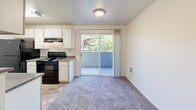 Located in Wilsonville, Oregon, this three-bedroom, two-bathroom apartment offers a practical and comfortable single-floor layout. The open-plan living and dining area is spacious and bright, finished with plush carpeting and neutral walls that create a clean, welcoming atmosphere. A sliding glass door connects this main living space directly to a private balcony, filling the room with natural light and offering pleasant views of surrounding greenery.

The kitchen features a galley-style design with wood-look flooring, white cabinetry, dark countertops, and black appliances including a range, refrigerator, and dishwasher. A pass-through peninsula opens the kitchen to the living area, enhancing the sense of openness.

The three bedrooms are carpeted and finished in soft neutral tones. The primary bedroom offers a generous footprint, while the additional bedrooms each include windows that bring in natural light. Five closets throughout the unit provide ample storage. Two full bathrooms each include a tub-shower combination with clean white surrounds and chrome fixtures.

Additional features include an in-unit laundry area and a dedicated hallway connecting the rooms. The overall design is straightforward and functional, well-suited for comfortable everyday living in the Meadows Loop community.