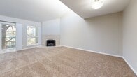 Located at 1801 E Girard Pl in Englewood, Colorado, this well-appointed two-bedroom, two-bathroom residence offers a comfortable and functional single-floor layout. The open kitchen is a standout feature, showcasing dark espresso cabinetry, granite countertops, a classic subway tile backsplash, and a full suite of stainless steel appliances including a refrigerator, range, microwave, and dishwasher. Light tile flooring ties the kitchen and living areas together seamlessly, while a distinctive arched window near the entry adds architectural character. The living room is generously sized, featuring vaulted ceilings that enhance the sense of openness, soft carpeting, and sliding glass doors that open to a private balcony with views of mature trees. Both bedrooms are carpeted and finished in neutral tones. The primary bedroom is spacious and includes dual closets and a window offering natural light and outdoor views. The second bedroom similarly benefits from natural light. Both bathrooms are finished with large-format stone-look tile surrounds on the tub and shower combinations, granite-topped vanities, and brushed nickel fixtures, lending a clean and polished aesthetic throughout.