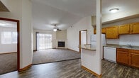 This single-floor residence offers a well-designed open-concept layout that seamlessly connects the living, dining, and kitchen areas. The spacious living room features vaulted ceilings, a ceiling fan with light fixture, a classic fireplace with a white mantel, and a large sliding glass door that invites natural light and outdoor views. Plush carpeting throughout the living area adds warmth and comfort.

The kitchen is efficiently designed with warm oak cabinetry offering generous storage, speckled laminate countertops, a double-basin sink, and white appliances including a refrigerator, electric range, over-the-range microwave, and dishwasher. A raised breakfast bar peninsula separates the kitchen from the main living space while maintaining an open feel. Durable wood-look flooring runs throughout the kitchen and entry areas.

The unit includes two carpeted bedrooms, both with windows that allow natural light. One bedroom features mirrored sliding closet doors, while the other is served by a spacious walk-in closet equipped with wire shelving and organizers. A full bathroom with a tub-shower combination and an additional bathroom with vinyl flooring complete the layout, providing practical and comfortable everyday living.