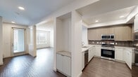 Located in Placentia, CA, this two-bedroom, three-bathroom residence is thoughtfully laid out across two floors, offering a comfortable and functional living environment. The main level features an open-concept design where the kitchen flows seamlessly into the living area. The kitchen is a standout space, outfitted with stainless steel appliances including a refrigerator, gas range, and built-in microwave, complemented by warm wood-tone upper cabinetry, white lower cabinets, a tile backsplash, and a generous light-colored countertop with an undermount sink. Recessed lighting set within a tray ceiling adds a refined touch. The living room benefits from natural light through blinds-fitted windows and features durable wood-style flooring that extends throughout the main level. A convenient half bathroom is also located on this floor. Upstairs, the two bedrooms are carpeted for comfort and each features its own closet, including a spacious walk-in closet with wire shelving in the primary bedroom. The upper level hosts two full bathrooms, one featuring a soaking tub and shower combination with clean white tile surround and wood-style flooring. The overall aesthetic is clean and contemporary, with a neutral white and warm beige palette throughout.