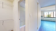 Located at 330 Oak Grove St in Minneapolis, Minnesota, this efficiently designed studio offers a thoughtfully organized single-floor layout comprising a living room, kitchen, bathroom, closet, and hallway. The living area is bright and open, featuring light-toned hardwood-style flooring and large windows that invite natural light and provide views of the surrounding Minneapolis neighborhood. Baseboard heating runs along the walls, ensuring comfort throughout the space. The kitchen is compact yet fully functional, outfitted with white cabinetry, a stainless steel sink, black appliances including a gas range and full-size refrigerator, and light wood flooring that ties seamlessly into the rest of the unit. A short hallway connects the main living area to the bathroom and closet. The bathroom features classic white square tile surrounding a full soaking tub and shower combination, complemented by tile flooring. Adjacent to the bathroom, the closet provides dedicated storage with built-in shelving. Clean white walls throughout the unit create a bright, neutral canvas. The overall ambiance is clean and functional, well-suited for urban living in the Loring Park neighborhood of Minneapolis.