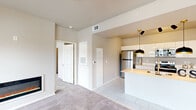 This single-story, 2-bedroom, 2-bathroom unit in Tulsa, Oklahoma offers a efficiently designed layout that maximizes functionality within a compact footprint. The living area features neutral-toned carpet, a sleek wall-mounted electric fireplace, and multiple windows with blinds that allow natural light to fill the space. A glass-paneled exterior door provides additional light and outdoor access directly from the living room.

The kitchen is designed with a modern aesthetic, showcasing high-gloss white cabinetry extending to the ceiling, light-toned countertops, and a full suite of stainless steel appliances including a refrigerator, electric range, and over-the-range microwave. Light tile flooring runs throughout the kitchen, which connects seamlessly to a peninsula with pendant lighting, reinforcing the open-concept design.

Both bedrooms feature plush carpet, neutral walls, and windows offering outdoor views. The primary bedroom includes a walk-in closet, while the second bedroom is equipped with a ceiling fan and a standard closet. A dedicated utility area with washer/dryer hookups and built-in shelving adds practicality to this well-appointed unit.