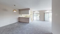 Located in the desirable West Los Angeles neighborhood of Rancho Park, this single-floor residence on Richland Avenue offers a well-designed layout with a comfortable, functional flow throughout. The open-concept living and dining area is generously proportioned, featuring soft carpeted flooring, warm neutral tones, and an eye-catching arched transom window above the sliding glass door that invites abundant natural light. A fireplace anchors one end of the living space, while the sliding doors provide direct outdoor access and views of surrounding greenery. The kitchen is thoughtfully laid out in a U-shape with white cabinetry, ample counter space, a gas range with built-in microwave, and a standout skylight overhead that brightens the workspace throughout the day. A peninsula counter seamlessly connects the kitchen to the living area, enhancing the open feel. The bedrooms are carpeted and spacious, with neutral walls and multiple closet access points. The bathrooms are clean and functional, each featuring a tub-shower combination with sliding glass enclosure, a single vanity with stone-look countertops, and large mirrors. A dedicated in-unit laundry closet with louvered doors is conveniently tucked within the hallway, adding practical everyday convenience to this well-appointed Los Angeles residence.