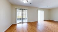 This two-story residence offers a practical and comfortable layout designed for everyday living. The main level features warm hardwood-style flooring that runs throughout the open living area, which is bathed in natural light through large sliding glass doors fitted with vertical blinds. A staircase leads to the upper floor, creating a clear separation between living and sleeping spaces. The galley-style kitchen is well-appointed with rich wood cabinetry lining both walls, generous counter space, a double-basin stainless steel sink, and white appliances including a gas range and refrigerator. The kitchen connects seamlessly to the living area, enhancing the overall flow of the main floor. Upstairs, the bedrooms feature plush wall-to-wall carpeting and neutral cream-toned walls, with windows providing outdoor views and allowing natural light to fill each room. The bathroom is finished with tile flooring, a granite-topped vanity with white cabinetry, and a full tub and shower combination enclosed by sliding glass doors. Throughout the home, textured ceilings, clean white trim, and a consistent neutral color palette create a cohesive and inviting atmosphere that is both functional and easy to personalize.