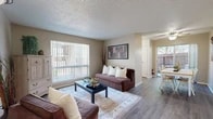 Located at 5327 Montgomery Blvd NE in Albuquerque, New Mexico, this efficient one-bedroom, one-bathroom residence offers a well-organized single-floor layout that maximizes every square foot. The living room serves as the heart of the home, featuring durable hardwood-style flooring, neutral warm-toned walls, and a textured ceiling. Large windows dressed with vertical blinds flood the space with natural light, while a sliding door provides access to an outdoor area, creating a seamless indoor-outdoor connection. A hallway connects the living area to the remaining rooms, maintaining a logical and functional flow throughout. The galley-style kitchen is efficiently designed with crisp white cabinetry, white countertops, a double sink, and black appliances including a range and refrigerator. A window above the counter brings in additional natural light. The bedroom offers a comfortable retreat with plush carpeting, a ceiling fan with light fixture, a closet, and a window overlooking a tree-lined outdoor view. The bathroom features tiled walls, a vanity with a light countertop, and a shower-tub combination. Throughout the residence, the design is clean and practical, making this a functional and inviting living space.