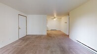 Located in Lynnwood, Washington, this one-bedroom, one-bathroom unit offers a practical and comfortable single-floor layout. The living room is a welcoming space highlighted by a tile-surround fireplace, neutral carpet flooring, and a sliding glass door that fills the room with natural light and provides views of the surrounding greenery. A baseboard heating system runs along the walls, ensuring year-round comfort, while a ceiling fan adds additional airflow. The galley-style kitchen is efficiently designed with white cabinetry trimmed in warm oak, white appliances including an electric range and refrigerator, white countertops, and wood-look vinyl flooring — offering ample cabinet and counter space for everyday cooking. The bedroom is a comfortably sized retreat featuring plush carpet, a large window with blinds for natural light, a built-in closet with sliding oak panel doors, and baseboard heating. The bathroom includes a full-size tub and shower combination, wood-look vinyl flooring, a single vanity with a mirror, and a tall storage closet with oak-toned doors. Throughout the unit, a consistent neutral color palette and warm wood accents create a cohesive and functional living environment.
