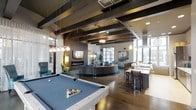 This single-floor amenity space is thoughtfully designed to blend social entertainment with relaxed comfort. Exposed dark wood ceiling beams add rustic character to the otherwise modern interior, while an array of pendant and track lighting creates a warm, inviting ambiance throughout. The open-plan layout is anchored by a full-size pool table with a blue felt surface, making it an immediate focal point upon entry. Adjacent to it, a generous circular lounge area features a curved sectional sofa set atop a teal area rug, centered around a sleek wall-mounted fireplace — ideal for gathering and conversation. A bar-height counter with seating provides a casual dining or socializing area, complemented by a well-appointed wet bar or kitchenette nearby. Large industrial-style windows along the perimeter allow abundant natural light to pour in, offering views of the surrounding outdoors. The flooring throughout is rich hardwood, adding warmth and continuity across the space. Curated artwork adorns the walls, and carefully chosen accent furniture in teal and gold tones contribute to the space's contemporary yet comfortable aesthetic. The overall design strikes a balance between a vibrant entertainment hub and a welcoming social retreat.