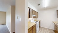 This single-story home features a practical and well-organized floor plan comprising three bedrooms, three bathrooms, a living room, kitchen, and hallway. The spacious living room is finished with wall-to-wall carpet and neutral beige walls, with a large window fitted with blinds that allows natural light to fill the room. A textured ceiling adds a classic touch to the space.

The galley-style kitchen is efficiently designed with warm wood-toned cabinetry, light-colored countertops, and white appliances including an electric range and refrigerator. Light vinyl plank flooring runs through the kitchen, providing a clean, easy-to-maintain surface.

The primary bedroom is generously sized, featuring carpet flooring, a ceiling fan, a window for natural light, and two closets offering ample storage. The two additional bedrooms are similarly carpeted, each equipped with a ceiling fan and a closet with built-in rods for hanging storage.

All three bathrooms are straightforward in design, with one featuring a clean white soaking tub and shower surround. A dedicated laundry area with vinyl plank flooring includes shelving and a dryer vent hookup, adding functional utility to the home. Throughout, the neutral color palette and consistent finishes create a cohesive and move-in ready environment.