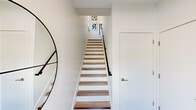 This contemporary three-story townhome in Novi, Michigan, offers a thoughtfully designed layout across three distinct levels, combining modern aesthetics with functional living. The entry level provides a welcoming foyer with striking wood-treaded stairs, black metal railings, and clean white walls that set a crisp, modern tone throughout.

The main living level serves as the heart of the home, featuring an open-concept kitchen and dining area with light grey cabinetry, stainless steel appliances, recessed lighting, and light wood flooring that flows seamlessly throughout. A spacious living room on this floor is filled with natural light and provides access to an outdoor area through sliding glass doors, offering pleasant views of surrounding greenery.

The upper level hosts two well-proportioned bedrooms, each with hardwood-style flooring and ample natural light from multiple windows. The primary bedroom is generously sized with dedicated closet space featuring built-in wire shelving. Four bathrooms are distributed across the floors, each finished with clean white walls, wood-style flooring, and natural light from windows.

Connecting all three levels, the open staircases with warm wood treads and sleek metal railings serve as a visual centerpiece. The overall design palette of crisp whites, natural wood tones, and modern fixtures creates a bright, airy ambiance throughout this well-appointed Novi townhome.