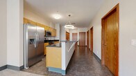Located at 44 Exchange Blvd in downtown Rochester, NY, this three-bedroom, two-bathroom unit offers a practical and well-appointed single-floor layout. The open-concept kitchen is a standout feature, equipped with stainless steel appliances including a French door refrigerator, electric range, and built-in microwave. Light wood cabinetry, dark stone countertops, and a central island with pendant lighting create a functional and modern cooking and dining space. Large-format tile flooring extends throughout the kitchen and hallway areas, lending a clean, cohesive look.

The unit includes three carpeted bedrooms, each with neutral tones and windows that allow natural light to filter in, including views of the surrounding urban streetscape. The primary bedroom offers a comfortable, generously sized retreat. The bathrooms are designed with accessibility in mind, featuring grab bars, a roll-in shower, wall-mounted sink, and mirrored medicine cabinet with tile flooring.

Additional spaces include a combined living and dining area, a pantry, a dedicated laundry area, and multiple closets for ample storage. Warm wood-toned doors throughout complement the unit's clean, neutral palette. The hallway connects all rooms in a straightforward, efficient layout well-suited for everyday living.