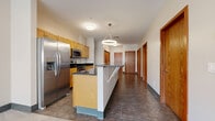 Located at 44 Exchange Blvd in downtown Rochester, NY, this three-bedroom, two-bathroom unit offers a practical and well-appointed single-floor layout. The open-concept kitchen is a standout feature, equipped with stainless steel appliances including a French door refrigerator, electric range, and built-in microwave. Light wood cabinetry, dark stone countertops, and a central island with pendant lighting create a functional and modern cooking and dining space. Large-format tile flooring extends throughout the kitchen and hallway areas, lending a clean, cohesive look.

The unit includes three carpeted bedrooms, each with neutral tones and windows that allow natural light to filter in, including views of the surrounding urban streetscape. The primary bedroom offers a comfortable, generously sized retreat. The bathrooms are designed with accessibility in mind, featuring grab bars, a roll-in shower, wall-mounted sink, and mirrored medicine cabinet with tile flooring.

Additional spaces include a combined living and dining area, a pantry, a dedicated laundry area, and multiple closets for ample storage. Warm wood-toned doors throughout complement the unit's clean, neutral palette. The hallway connects all rooms in a straightforward, efficient layout well-suited for everyday living.