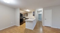 This single-floor residence offers a thoughtfully designed layout with 2 bedrooms and 2 full bathrooms. The kitchen is a functional centerpiece, featuring dark espresso cabinetry, black appliances including a refrigerator, stove, and microwave, and a peninsula with a light-toned countertop that provides additional prep space and a casual dining option. Warm wood-look flooring flows throughout the main living areas, lending a cohesive and inviting feel. The living room is bright and open, highlighted by French doors that let in natural light and offer access to the outdoors, complemented by a ceiling fan overhead. Both bedrooms are carpeted for comfort, each equipped with a ceiling fan and a closet. The primary bedroom is generously sized, offering ample space for furnishings. The two bathrooms are finished with wood-look flooring, dark vanity cabinetry, light countertops, a large mirror, and a tub-shower combination with tile surround and grab bars — a practical and accessible detail. Clean neutral walls and white trim throughout create a bright, move-in-ready atmosphere across the entire residence.