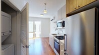 Located at 4736 N Winthrop Ave in Chicago's vibrant Uptown neighborhood, this modern single-floor unit showcases a clean, contemporary design throughout. Rich hardwood flooring flows seamlessly across the open-concept living and kitchen areas, creating a warm and cohesive atmosphere.

The kitchen is thoughtfully appointed with stainless steel appliances, including a Bloomberg refrigerator, gas range, and built-in microwave. Light wood and gray cabinetry is complemented by white subway tile backsplash and open shelving, while pendant lighting adds a stylish finishing touch. A wall-mounted mini-split HVAC unit ensures year-round climate comfort.

The living area is bright and open, bathed in natural light from large glass doors that lead to a private outdoor balcony, offering views of the surrounding modern building facade. The crisp white walls and clean lines throughout lend the space an airy, minimalist feel.

The bathroom features a navy blue vanity with a white countertop, a mirrored medicine cabinet, and neutral gray tile flooring, delivering a modern and functional finish. A dedicated closet area off the kitchen provides convenient storage. The unit's layout is efficient and well-designed, making excellent use of the available space while maintaining a comfortable, contemporary living environment.