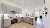 Located on East Colfax Avenue in Denver, Colorado, this thoughtfully designed one-bedroom, one-bathroom residence offers a clean, modern aesthetic throughout. Light hardwood-style flooring flows seamlessly across the open-concept layout, connecting the kitchen and living area in a bright, cohesive space.

The kitchen is well-appointed with gray shaker cabinetry extending to the ceiling, white quartz countertops, a classic subway tile backsplash, and stainless steel appliances — providing both style and functionality. The adjacent living area is bathed in natural light from floor-to-ceiling glass doors that open to a private balcony, offering outdoor views and a strong indoor-outdoor connection.

The bedroom is a calm, comfortable retreat featuring sheer curtains framing a large window with balcony access, plush carpeting, and geometric wall art that adds visual interest. The bathroom is sleek and elongated, finished with gray cabinetry, a backlit mirror, quartz countertops, and a glass-enclosed shower. A dedicated walk-in closet connects directly to the bathroom for added convenience.

Tall ceilings, crisp white walls, and abundant natural light lend the entire space an airy, open quality. The entryway is clean and minimal, featuring light hardwood floors and ample wall space. This residence combines modern finishes with a warm, inviting ambiance in the heart of Denver.