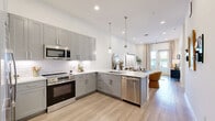 Located on East Colfax Avenue in Denver, Colorado, this thoughtfully designed one-bedroom, one-bathroom residence offers a clean, modern aesthetic throughout. Light hardwood-style flooring flows seamlessly across the open-concept layout, connecting the kitchen and living area in a bright, cohesive space.

The kitchen is well-appointed with gray shaker cabinetry extending to the ceiling, white quartz countertops, a classic subway tile backsplash, and stainless steel appliances — providing both style and functionality. The adjacent living area is bathed in natural light from floor-to-ceiling glass doors that open to a private balcony, offering outdoor views and a strong indoor-outdoor connection.

The bedroom is a calm, comfortable retreat featuring sheer curtains framing a large window with balcony access, plush carpeting, and geometric wall art that adds visual interest. The bathroom is sleek and elongated, finished with gray cabinetry, a backlit mirror, quartz countertops, and a glass-enclosed shower. A dedicated walk-in closet connects directly to the bathroom for added convenience.

Tall ceilings, crisp white walls, and abundant natural light lend the entire space an airy, open quality. The entryway is clean and minimal, featuring light hardwood floors and ample wall space. This residence combines modern finishes with a warm, inviting ambiance in the heart of Denver.
