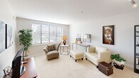This thoughtfully laid-out one-bedroom, one-bathroom residence at 15101 Ford Rd in Dearborn, MI offers a comfortable and efficient living experience across a single floor. The open-concept living room is bright and welcoming, featuring plush carpeting, neutral walls, and large windows with horizontal blinds that invite an abundance of natural light and views of the surrounding greenery. The space flows naturally from a relaxed seating area into the rest of the home. The kitchen is efficiently designed with warm honey-toned cabinetry, light countertops, tile flooring, and white appliances including a refrigerator, stove, and microwave. A peninsula-style counter provides additional workspace, while recessed lighting keeps the area well-lit. A freestanding shelving unit defines the boundary between the kitchen and living areas, adding both function and character. The generously sized primary bedroom features soft carpet, light blue walls, and a large window that fills the room with natural light. A dedicated closet provides ample storage. The bathroom is finished with warm travertine-style tile, a glass-enclosed walk-in shower with chrome fixtures and grab bars, a single-sink vanity, and tile flooring — combining practicality with a clean, polished aesthetic throughout.