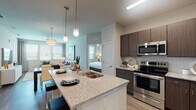 This thoughtfully designed single-floor residence offers a seamless blend of modern aesthetics and functional living. The open-concept layout connects the kitchen and living areas, creating a cohesive and inviting atmosphere throughout.

The kitchen is a standout feature, showcasing rich dark wood cabinetry, light granite countertops, and a full suite of stainless steel appliances, including a range, microwave, and refrigerator. A large island with a double sink provides generous prep space and doubles as a casual dining area with bar seating. Light wood-style flooring runs throughout the main living areas, adding warmth and continuity.

The living room is bright and welcoming, featuring multiple windows that invite natural light and offer outdoor views. A ceiling fan adds comfort, and the space is well-suited for both relaxing and entertaining.

Each bedroom is carpeted and generously sized, with large windows that allow ample natural light. Both bedrooms are serviced by their own bathrooms, each appointed with granite-topped vanities, dark wood cabinetry, and walk-in closets with built-in shelving. One bathroom features a glass-enclosed walk-in shower, while the other offers a combined configuration. The overall ambiance is contemporary, clean, and comfortable throughout.