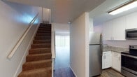 This two-story residence offers a well-organized layout spread across two levels, combining updated finishes with functional living spaces. The main level features rich hardwood-style flooring that flows throughout the open living and dining areas. A sliding glass door in the living room fills the space with natural light while providing views of the outdoors, complemented by vertical blinds for privacy. The kitchen is a standout feature, appointed with crisp white shaker cabinetry, granite stone countertops, a stainless steel sink, and stainless steel appliances including a refrigerator, range, microwave, and dishwasher. A window above the sink brings in additional natural light. Also on the main level is a bathroom featuring a granite-topped vanity with white cabinetry and hardwood-style flooring. Carpeted stairs lead to the upper level, where the bedrooms are finished with plush carpet, ceiling fans, and windows that invite natural light. Each bedroom offers a comfortable and quiet retreat. Throughout the home, textured ceilings add a classic touch, while ample built-in storage and closet space contribute to the overall practicality of this thoughtfully designed two-story residence.