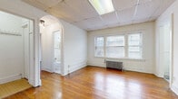 Located at 2808 Mayfield Rd in Cleveland Heights, OH, this one-bedroom, one-bathroom unit offers a thoughtfully laid-out single-floor plan encompassing a living room, bedroom, kitchen, bathroom, closet, and hallway. The living room is a bright, open space featuring warm hardwood floors, a triple-pane window that draws in natural light, a classic cast iron radiator, and a drop tile ceiling with flush lighting. An elegant arched doorway connects the living area to the hallway, adding a charming architectural detail. The spacious bedroom continues the hardwood flooring and includes its own cast iron radiator, a natural light-filled window, and two dedicated closets with hanging rods for ample storage. The kitchen has been updated with white cabinetry, granite-look countertops, a matte black faucet with a deep sink, gray luxury vinyl plank flooring, open shelving, and pendant lighting, giving it a clean, modern feel. The bathroom retains its classic character with floor-to-ceiling white subway tile accented by blue trim, a hexagonal mosaic tile floor, a soaking tub with shower, and a vanity with mirror. Throughout the unit, the blend of original hardwood floors and period-appropriate cast iron radiators creates a warm, character-rich atmosphere.