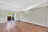 Located at 23251 Los Alisos Blvd in Lake Forest, CA, this well-maintained single-floor residence offers a thoughtful layout with one bedroom and one bathroom. The living room is a bright, open space highlighted by rich hardwood flooring, a textured ceiling, and a sliding glass door that opens onto a private balcony overlooking lush, mature greenery — providing a serene outdoor backdrop. The kitchen features white cabinetry, granite-look countertops, a double stainless steel sink, recessed lighting, and hardwood floors, offering a clean and functional workspace. A connecting hallway with additional counter space links the kitchen to the rest of the unit. The spacious primary bedroom is carpeted for comfort and includes a ceiling fan with light, mirrored sliding closet doors, a built-in desk area, and multiple windows that bring in abundant natural light and garden views. The bathroom is clean and well-lit, featuring wood-look flooring, a white vanity with a wide mirror, and a full tub and shower combination. Throughout the residence, a neutral color palette and consistent finishes create a cohesive, move-in ready environment.