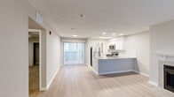 Located at 765 Polk Dr in Arlington, TX, this one-bedroom, one-bathroom residence offers a thoughtfully designed layout across a single floor. The open-concept living and kitchen area serves as the heart of the home, featuring light wood-style flooring, neutral gray tones, and recessed lighting throughout. Large windows and a sliding glass door to the balcony invite generous natural light into the living space, which is anchored by a tiled fireplace with a classic white mantel — a standout architectural detail.

The kitchen is well-appointed with white shaker cabinetry, a white subway tile backsplash, light quartz countertops, and a peninsula island with an undermount sink. Stainless steel appliances, including a refrigerator, electric range, and microwave, complete the modern cooking space.

The bedroom offers a comfortable retreat with plush carpeting, a sliding-door closet with built-in hanging rods, and a window for natural light. The bathroom includes a full tub-shower combo with floor-to-ceiling tile surround and brushed nickel fixtures. A hallway connects the main living areas, providing a practical flow throughout the unit.