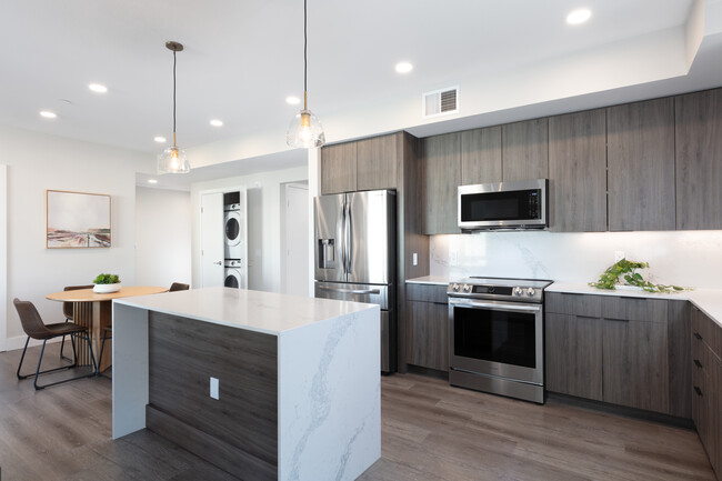 Signature Collection Kitchen with wood cabinetry, marbled quartz countertop and backsplash, upgraded stainless steel appliances, and hard surface flooring - Avalon West Dublin