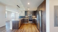 Located at 237 S Dixie Hwy in the heart of Coral Gables, FL, this thoughtfully designed single-floor unit offers a sleek, modern aesthetic throughout. The chef's kitchen is a standout feature, showcasing rich dark wood cabinetry that extends to the ceiling, granite countertops, a stylish tile backsplash, and a full suite of stainless steel appliances including a range, microwave, and French door refrigerator. Elegant geometric pendant lights hang above the kitchen island, adding a contemporary touch. Warm hardwood-style flooring flows seamlessly through the main living areas and bedrooms, complementing the clean white walls and recessed lighting. The bedrooms are generously sized and bathed in natural light from large windows that frame panoramic views of the Coral Gables skyline and surrounding greenery. A bright, airy hallway connects the rooms, leading toward a glass-door balcony that invites additional natural light. The bathrooms are finished with granite-topped dark wood vanities, large-format tile flooring, and tub-shower combinations clad in warm earth-tone tile. The overall ambiance is clean, contemporary, and light-filled, reflecting refined urban living in one of Miami-Dade's most desirable neighborhoods.