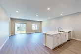 Located on NW Linosa Dr in Waukee, Iowa, this single-story home offers a thoughtfully designed floor plan with three bedrooms, two bathrooms, and a dedicated laundry room. The open-concept kitchen and living area forms the heart of the home, showcasing light-toned luxury vinyl plank flooring, recessed lighting, and large sliding glass doors that invite natural light and provide outdoor access. The kitchen is outfitted with white shaker-style cabinetry, white quartz countertops, stainless steel appliances including a refrigerator, range, and microwave, and a central island with a built-in sink. A clean, well-lit hallway connects the bedrooms and bathrooms, maintaining a consistent neutral color palette throughout. The spacious primary bedroom features plush carpeting and is complemented by a private en-suite bathroom with a double-sink vanity, wood-look flooring, and a walk-in shower. A generously sized walk-in closet with wire shelving provides ample storage. Additional bedrooms are carpeted and offer comfortable proportions. The dedicated laundry room includes a full-size washer and dryer with overhead shelving. The attached two-car garage features an automatic opener and provides substantial additional storage and parking space.