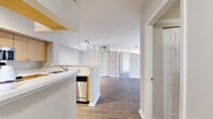 Located at 1010 NW Fresco Way in Stuart, Florida, this single-floor, three-bedroom, two-bathroom home offers a functional and well-organized layout. The open-concept kitchen and living area serves as the heart of the home, with the kitchen featuring light wood cabinetry, white countertops, stainless steel appliances including a refrigerator, range, built-in microwave, and dishwasher, along with a peninsula that provides additional prep space and separates the kitchen from the living area. The living room is bright and airy, with wood-look flooring throughout and a sliding glass door that invites natural light and provides access to outdoor greenery. The bedrooms are comfortably sized, with the primary bedroom offering notable space, while each room features neutral-toned walls, wood-look flooring, and windows with blinds that allow for natural light and outdoor views of the surrounding landscape, including tropical foliage. Ceiling fans are present in select rooms for added comfort. The bathrooms are clean and functional, with one featuring a full tub-shower combination, a wide vanity mirror, and modern fixtures. A dedicated closet provides convenient storage. The overall aesthetic is clean and modern, with a neutral color palette throughout.