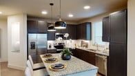 Located in Round Rock, TX, this thoughtfully designed two-bedroom, two-bathroom residence features a single-floor layout that balances functionality and modern style throughout. The entryway welcomes you with wood-look plank flooring and a clean, bright hallway that connects the living spaces seamlessly.

The kitchen is a standout, showcasing dark espresso shaker cabinets, granite countertops, a subway tile backsplash, and a full suite of stainless steel appliances. A center island with pendant lighting serves as both a prep space and casual gathering spot.

The living area is filled with natural light from large windows and a sliding glass door that opens to a private balcony offering open, scenic views of the surrounding landscape.

Both bedrooms feature plush carpet, ceiling fans, and generous windows. The primary bedroom connects to an en-suite bathroom with a double-sink granite vanity, dark cabinetry, wood-look flooring, and a glass-enclosed walk-in shower. The second bathroom mirrors the refined finishes with a granite vanity and ample storage cabinetry.

Throughout the home, neutral tones, recessed lighting, and consistent high-quality finishes create a cohesive and inviting atmosphere well-suited for comfortable everyday living.