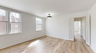 This single-floor, 3-bedroom, 1-bathroom residence offers a bright and clean living environment defined by a consistent, modern aesthetic. Light-toned hardwood flooring flows throughout the main living areas and all three bedrooms, creating a cohesive and airy feel. The white walls reflect natural light generously admitted through multiple windows, many of which offer views of the surrounding brick buildings.

The spacious primary bedroom is a standout feature, offering generous proportions, dual windows for abundant natural light, a pendant light fixture, and louvered closet doors. The two additional bedrooms are well-sized, each featuring hardwood floors, bright white walls, and windows that bring in daylight.

The kitchen is appointed with white cabinetry featuring matte black hardware, a subway tile backsplash, light marble-style countertops, a black faucet with an undermount sink, and large-format tile flooring — combining a fresh, contemporary look with functional design.

The full bathroom features classic yellow square wall tiles, contrasting marble-style tub surround tiles, a white vanity with under-cabinet storage, a matte black faucet, and a mirrored medicine cabinet above — offering a retro-inspired character.

A hallway connects all rooms, contributing to an efficient and practical floor plan. Overall, the space presents a well-maintained, light-filled home with updated finishes throughout.