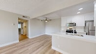 Located in Valencia, CA, this single-floor 2-bedroom, 2-bathroom residence offers a clean, modern aesthetic throughout. The open-concept layout seamlessly connects the living room, dining area, and kitchen into one bright, airy space finished with light wood-style flooring and a textured ceiling. A ceiling fan anchors the living area, while a sliding glass door leads to a private patio, allowing natural light to pour in.

The kitchen is well-appointed with crisp white shaker cabinetry, white quartz countertops, a subway tile backsplash, and a full suite of stainless steel appliances including a gas range, built-in microwave, refrigerator, and dishwasher. A peninsula with an undermount sink adds additional prep space and casual seating potential. A dedicated pantry provides extra storage.

Both bedrooms feature plush carpeting and mirrored sliding closet doors. The primary bedroom is comfortably sized with a natural light window. The two bathrooms are finished with white vanities, quartz countertops, and modern chrome fixtures. Additional highlights include in-unit laundry, a hallway connecting all rooms, and multiple closets throughout for ample storage.