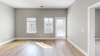 Located at 30 Market St SW in Concord, NC, this well-appointed one-bedroom, one-bathroom unit offers a thoughtfully designed open-concept layout across a single floor. The living area is bright and airy, featuring light-toned hardwood-style flooring, soft gray walls, and multiple windows with slatted blinds that allow natural light to pour in. A glass-paneled door adds an additional connection to the outside.

The kitchen is a standout feature, showcasing a peninsula with granite countertops and an undermount sink, complemented by sleek pendant lighting overhead. Light wood cabinetry pairs with a full suite of stainless steel appliances, including a range, microwave, dishwasher, and refrigerator, creating a functional and modern cooking space that flows seamlessly into the living area.

The bedroom offers a comfortable, carpeted retreat complete with a ceiling fan, natural light from a window, and direct sightlines to the kitchen — giving the space an open, connected feel.

The bathroom features warm hardwood-style flooring, a granite-topped vanity with contemporary cabinetry, a large mirror, and clean white fixtures, providing a polished and practical space. Throughout the unit, consistent neutral tones and quality finishes create a cohesive, modern ambiance ideal for comfortable everyday living.