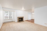 This single-floor residence offers a thoughtfully laid-out living space with a clean, neutral aesthetic throughout. The living room serves as a central gathering area, highlighted by a tile-surround fireplace and plush carpeting underfoot. Natural light filters in through a window, while a baseboard heating system ensures year-round comfort. A sliding door provides additional access, connecting the living area to adjacent spaces.

The kitchen is efficiently designed with white cabinetry, dark granite-style countertops, and hardwood-style flooring. It is equipped with a full suite of white appliances, including a refrigerator, electric range, and over-the-range microwave. A double-basin stainless steel sink sits beneath a window, and a breakfast bar adds casual dining functionality.

The bedrooms are generously sized, each featuring plush carpeting, windows with blinds for natural light and privacy, and baseboard heating. The rooms offer a bright, open feel with crisp white walls.

The bathrooms feature white cabinetry with granite-style countertops, undermount sinks, and hardwood-style flooring. One bathroom includes a shower/tub combination, providing full functionality. The overall design of the unit is consistent and cohesive, emphasizing clean lines, neutral tones, and practical finishes throughout.