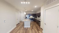 Located at 751 N Main St in Mansfield, Texas, this thoughtfully designed single-floor residence offers a contemporary living experience with high-quality finishes throughout. The open-concept kitchen serves as the heart of the space, showcasing rich dark espresso cabinetry, light granite countertops, a central island with pendant lighting overhead, and a full suite of stainless steel appliances including a French door refrigerator, electric range, built-in microwave, and dishwasher. Wood-look plank flooring runs throughout the main living areas, adding warmth and a cohesive aesthetic. The living area is bright and welcoming, featuring French doors with transom windows that invite natural light and provide outdoor access, complemented by a ceiling fan overhead. The bedroom offers plush carpeting, dual windows, and a ceiling fan, creating a comfortable and restful retreat. The bathroom is equipped with accessibility features including grab bars and a tub with handheld shower, alongside granite countertops. A dedicated walk-in closet with built-in shelving provides generous storage. Clean white walls, modern door hardware, and consistent design details tie the entire space together into a polished, move-in-ready residence.
