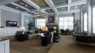 This refined single-floor space exudes a classic, upscale ambiance defined by thoughtful architectural details and carefully curated furnishings. The centerpiece of the main lounge area is a striking coffered ceiling, painted in a sophisticated slate blue and white palette, which adds depth and visual interest overhead. A dramatic multi-tiered chandelier with candle-style lighting hangs as a focal point, complemented by warm wall sconces that cast a welcoming glow throughout the room. The stone fireplace serves as a natural gathering anchor, flanked by large windows dressed with white shutters that invite abundant natural light while maintaining an air of privacy. Seating arrangements include plush sofas and upholstered chairs in neutral tones, thoughtfully grouped around dark espresso-finished accent tables to encourage conversation and relaxation. A separate dining nook with dark bistro-style chairs and a round table sits near the windows, offering a more intimate setting. Lush potted plants punctuate the space, adding life and texture. The overall atmosphere is warm, polished, and inviting — ideal for both social gatherings and quiet moments of retreat.
