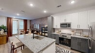 Located at 6615 Cerris Dr in Charlotte, NC, this thoughtfully designed one-bedroom, one-bathroom unit offers a well-appointed layout across a single floor. The kitchen is a standout feature, boasting two-tone cabinetry with white upper and gray lower cabinets, granite countertops, a subway tile backsplash, stainless steel appliances, and a central island with a undermount sink — ideal for both cooking and casual dining. Wood-look flooring runs throughout the main living areas, adding warmth and continuity. The living room makes a striking impression with a bold botanical-patterned accent wall, recessed lighting, and a glazed door that welcomes natural light. The bedroom offers plush carpeting, a ceiling fan, and a decorative paneled accent wall, creating a calm and comfortable retreat. The bathroom is finished with gray cabinetry, granite countertops, black hardware accents, a tiled shower, and wood-look flooring. A dedicated laundry area houses a stacked washer and dryer unit with overhead shelving for added storage convenience. Clean white walls, consistent finishes, and modern fixtures give this unit a cohesive, contemporary aesthetic throughout.