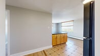 Located at 101 N Grant St in Denver, Colorado, this two-bedroom, one-bathroom residence offers a practical and well-organized single-floor layout. The combined kitchen and living area serves as the heart of the home, featuring light wood cabinetry, black appliances including a refrigerator, range, and over-the-range microwave, and a patterned tile floor that adds visual interest. A window allows natural light to brighten the kitchen area, creating an inviting atmosphere.

A hallway connects the main living space to the rest of the unit, leading to two bedrooms and the shared bathroom. Both bedrooms are carpeted and equipped with ceiling fans for added comfort. Each room features large windows dressed with wood-framed blinds that frame elevated views of the Denver cityscape and surrounding greenery. Wall-mounted HVAC units provide individual climate control in the bedrooms. One bedroom includes a spacious double-door closet, offering ample storage. The second bedroom features light hardwood-style flooring and similarly expansive views.

The bathroom is finished with neutral beige tile surrounding a full tub and shower combination, complete with grab bars and a handheld showerhead. The overall design is clean and functional, making efficient use of the available space throughout.