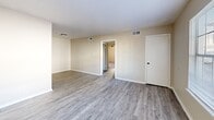 This two-bedroom, one-bathroom unit in Memphis, Tennessee offers a well-organized single-floor layout with modern updates throughout. The combined kitchen and living area serves as the heart of the home, with the living room featuring neutral-toned walls, wood-look luxury vinyl plank flooring, a textured ceiling, and a window that brings in natural light. The kitchen is a standout space, designed in a galley style with white cabinetry accented by black hardware, granite countertops, a subway tile backsplash, a deep single-basin sink with a matte black faucet, and a full suite of black appliances including a range, over-the-range microwave, and refrigerator. Both bedrooms are carpeted and share a calm, neutral palette, each equipped with a ceiling fan and a window for ventilation and natural light. One bedroom includes a built-in closet with double rods for added storage. The full bathroom features a granite-topped vanity with an undermount sink, matte black fixtures, a tiled tub-and-shower combination, and tile flooring. A hallway connects the primary living areas to the bedrooms and bathroom, completing the efficient floor plan.