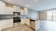 This single-floor space offers a clean, contemporary design with a well-appointed open-concept kitchen as its centerpiece. The kitchen is outfitted with white shaker-style cabinetry extending to the upper walls, providing generous storage throughout. Dark granite countertops contrast neatly against the white cabinetry, and a peninsula with a built-in sink adds functional workspace while visually connecting the kitchen to the adjoining living area. A full suite of stainless steel appliances — including a refrigerator, electric range, over-the-range microwave, and dishwasher — completes the kitchen. Light wood-look flooring runs throughout the main living and kitchen areas, lending a bright, cohesive feel to the open layout.

The bedroom features soft, neutral-toned carpet and multiple windows that invite natural light and provide outdoor views, creating a calm and restful atmosphere. The full bathroom is finished with wood-look tile flooring, a white shaker-style vanity with storage, a full tub-shower combination, and a built-in linen cabinet, offering both practicality and a clean aesthetic. Recessed lighting throughout the unit, neutral wall tones, and consistent finishes give the space a polished, move-in-ready appearance.